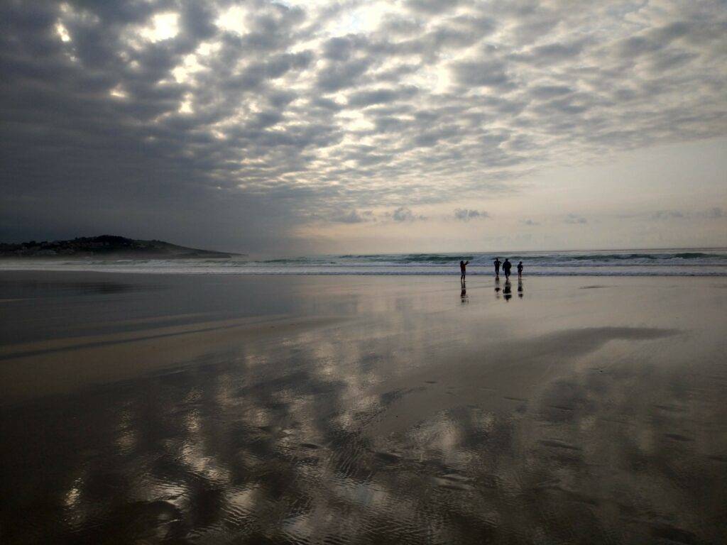 oyambre beach clouds reflecting in wet sand